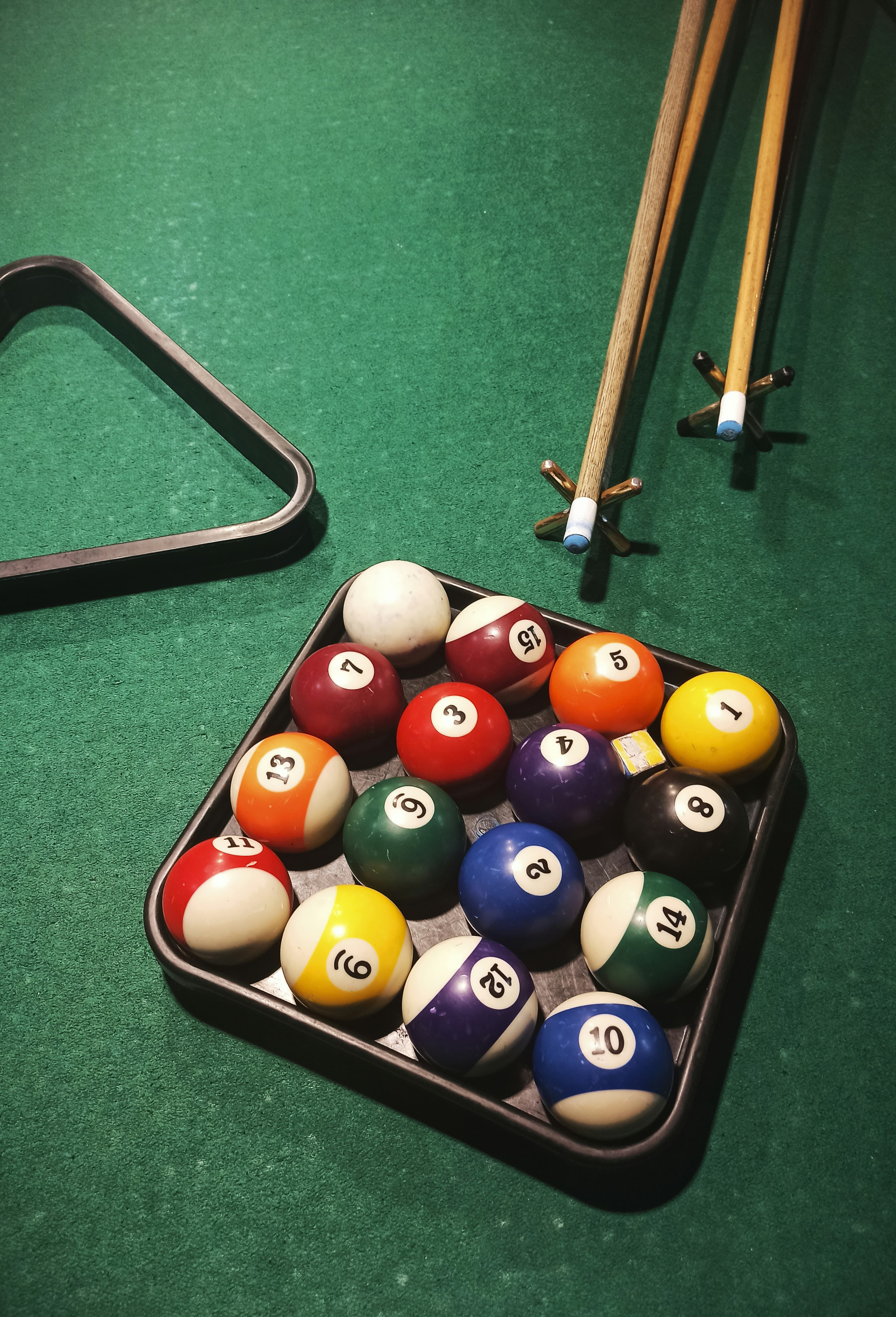 Bolas de billar numeradas junto a tacos y triángulo